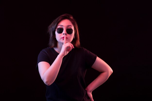 Jeune femme avec un T-shirt noir demandant le silence