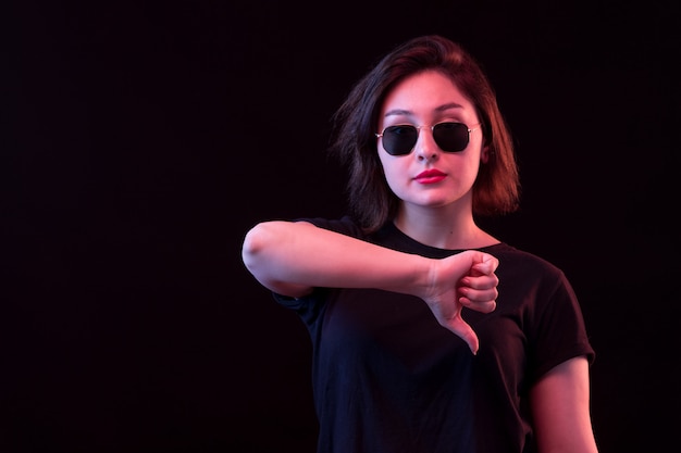 Jeune femme avec un T-shirt noir avec le pouce vers le bas