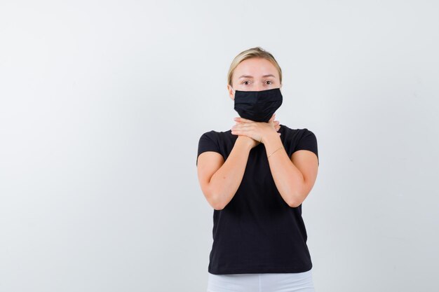 Jeune femme en t-shirt, pantalon, masque médical s'étouffant et ayant l'air fatigué