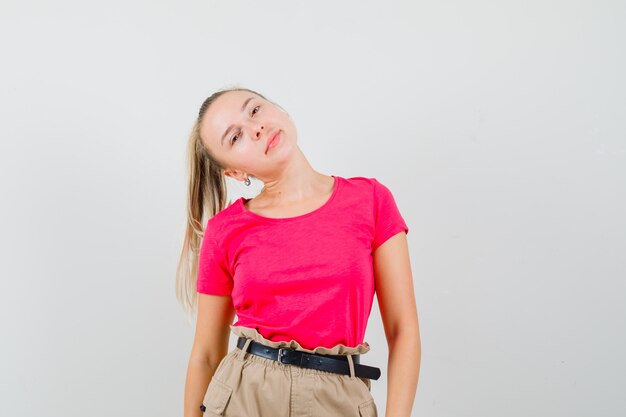 Jeune femme en t-shirt et pantalon s'inclinant la tête sur l'épaule et à la belle