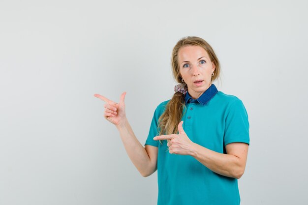 Jeune femme en t-shirt pointant vers le côté et à la curiosité