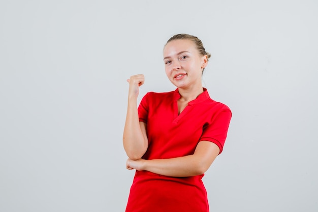 Jeune femme en t-shirt rouge pointant vers l'arrière avec le pouce et à la joyeuse