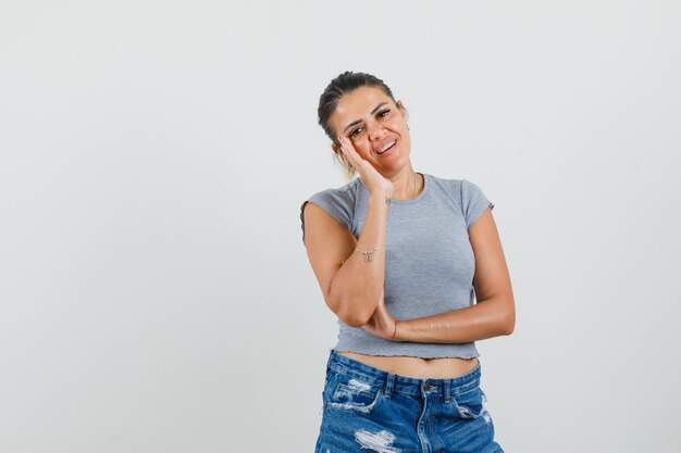 Jeune femme en t-shirt, short debout dans la pensée pose et à la recherche sensible