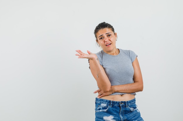 Jeune femme en t-shirt, short étalant la paume de côté et à la confusion