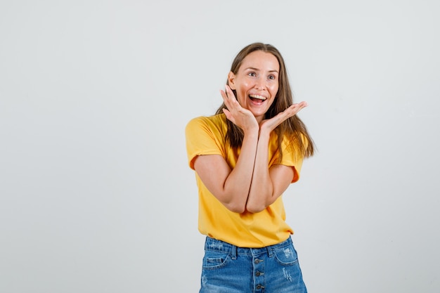 Jeune femme en t-shirt, short main dans la main près du visage et à la joyeuse