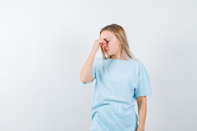 Jeune femme en t-shirt souffrant de maux de tête et à la vue épuisée, de face.