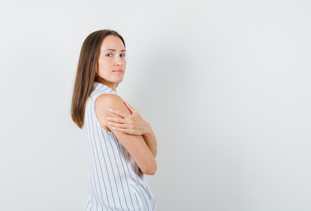 Jeune femme en t-shirt tenant la main sur l'autre bras et à la confiance.