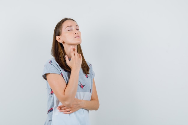 Jeune Femme En T-shirt Touchant Le Mal De Gorge Avec Les Doigts, Vue De Face.