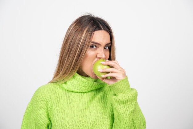 Jeune femme en t-shirt vert mangeant une pomme