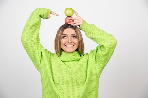 Jeune femme en t-shirt vert tenant deux pommes au-dessus.