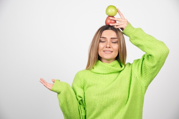 Jeune femme en t-shirt vert tenant deux pommes au-dessus