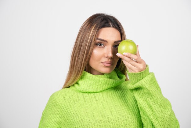 Jeune femme en t-shirt vert tenant une pomme.