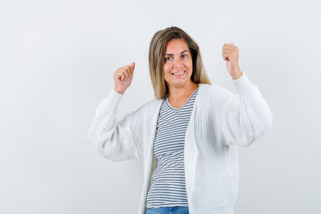 Jeune femme en t-shirt, veste montrant le geste du gagnant et à la joyeuse vue de face.