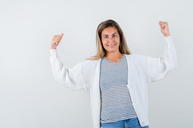 Jeune femme en t-shirt, veste montrant les muscles des bras et l'air confiant, vue de face.