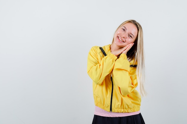 Jeune femme en t-shirt, veste penchée joue sur les mains et à la recherche positive