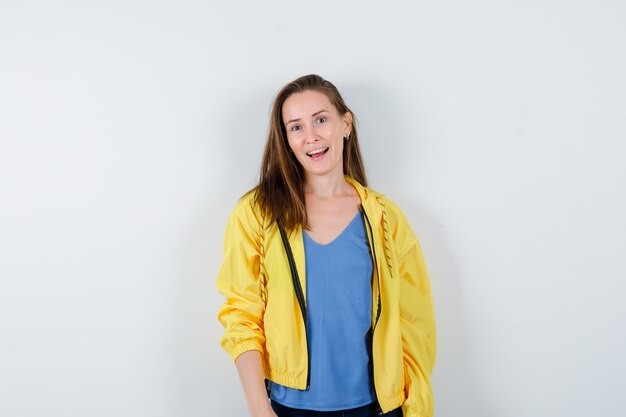 Jeune femme en t-shirt, veste regardant la caméra et charmante, vue de face.