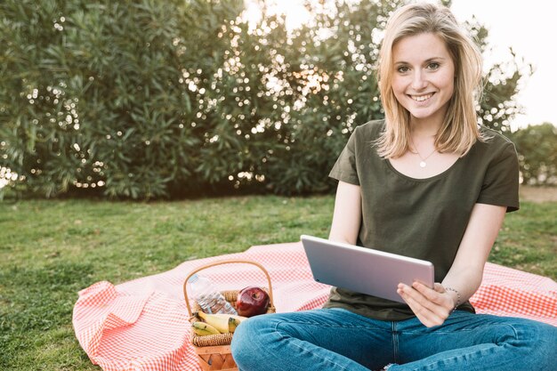 Jeune femme avec tablette en regardant la caméra