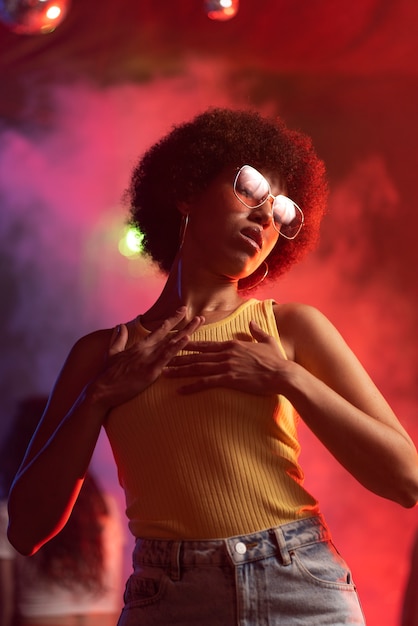 Une jeune femme de taille moyenne danse à une fête techno.