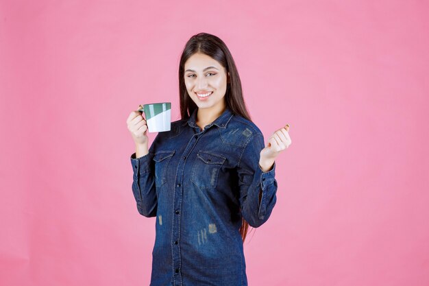 Jeune femme, à, a, tasse café, sourire, et, sentiment positif