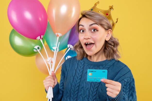 jeune femme tenant des ballons et carte bancaire sur jaune