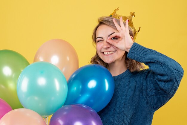 jeune femme tenant des ballons en couronne sur jaune