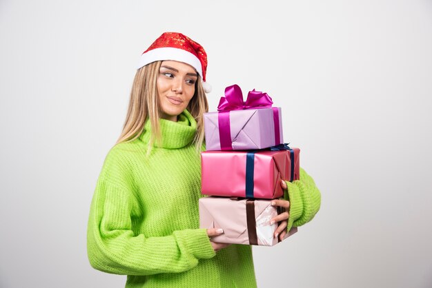 Jeune femme tenant beaucoup de cadeaux de Noël festifs.