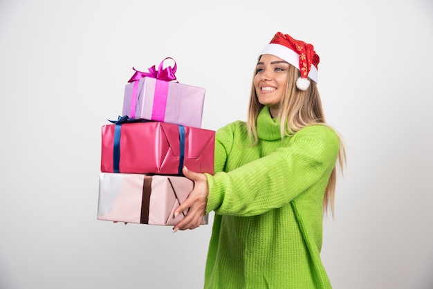 Jeune femme tenant beaucoup de cadeaux de Noël festifs.