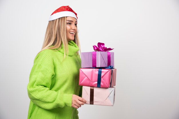 Jeune femme tenant beaucoup de cadeaux de Noël festifs.