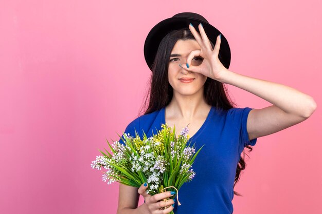 Jeune femme tenant un bouquet de fleurs et regardant à travers ses doigts