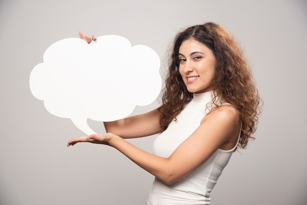 Photo gratuite jeune femme tenant une bulle de dialogue blanc vide vide. photo de haute qualité