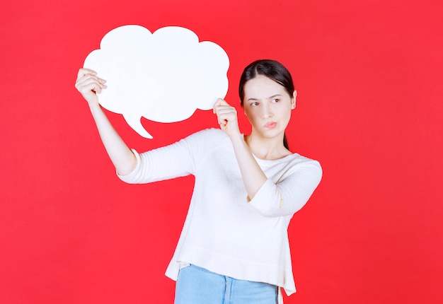 Jeune femme tenant une bulle de dialogue avec une forme de nuage