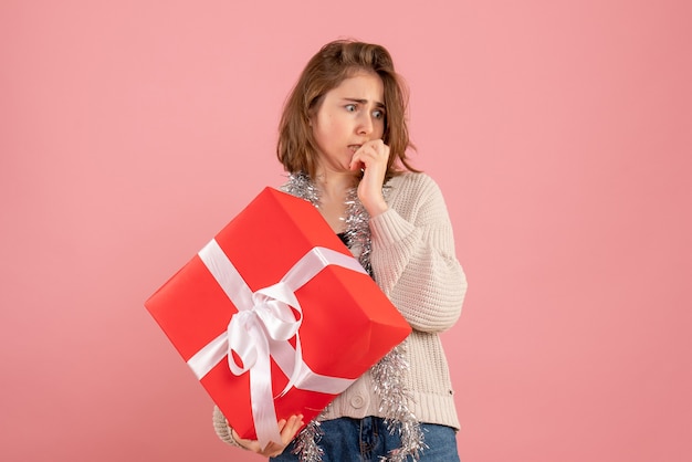 jeune femme tenant un cadeau de Noël dans ses mains sur rose