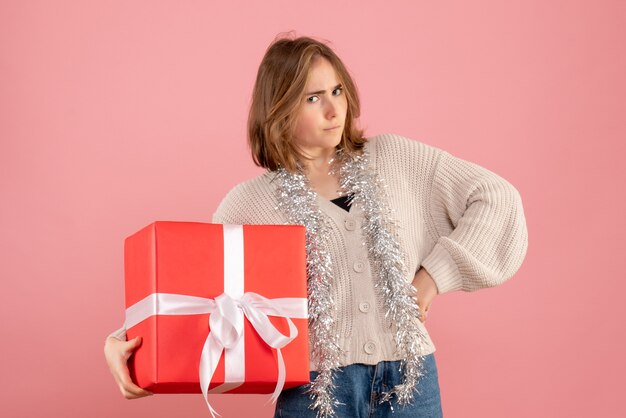 jeune femme tenant un cadeau de Noël dans ses mains sur rose