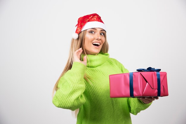 Jeune femme tenant un cadeau de Noël festif.