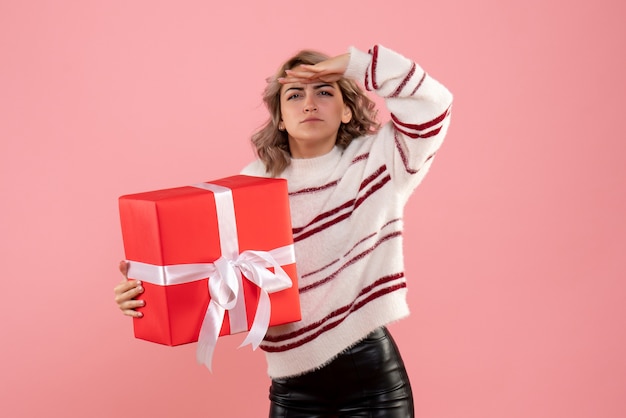 jeune femme tenant un cadeau de Noël et à la recherche de rose