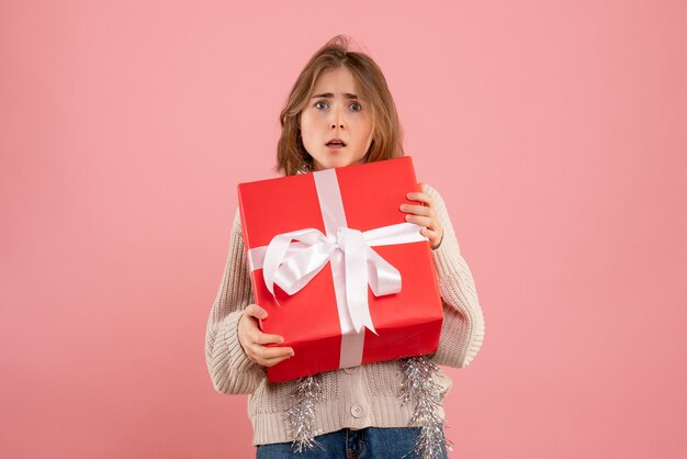 jeune femme tenant un cadeau de Noël sur rose