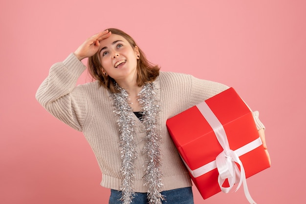 jeune femme tenant un cadeau de Noël sur rose