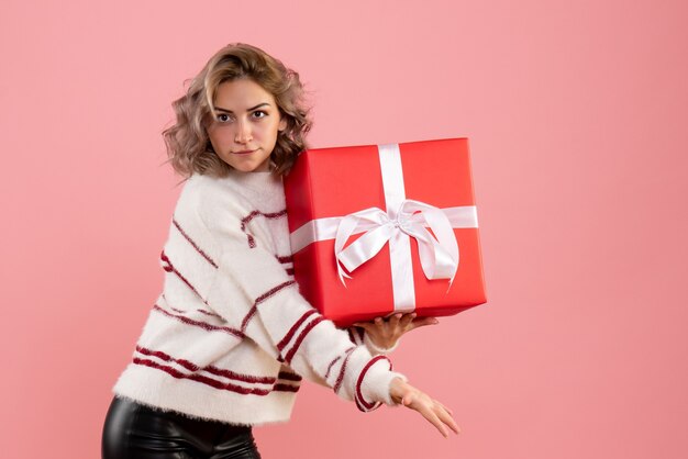 jeune femme tenant un cadeau de Noël sur rose