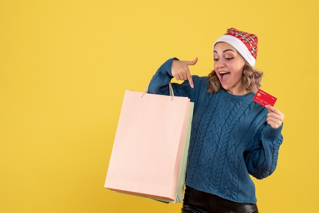 jeune femme tenant une carte bancaire et des paquets après le shopping sur jaune