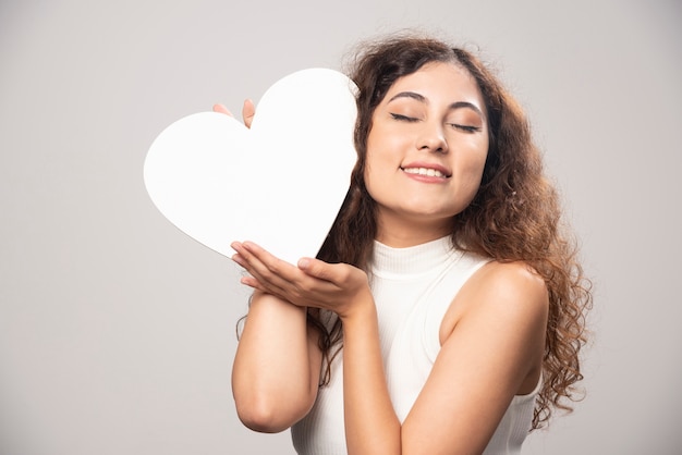 Jeune femme tenant un coeur de papier fait main blanc. Photo de haute qualité