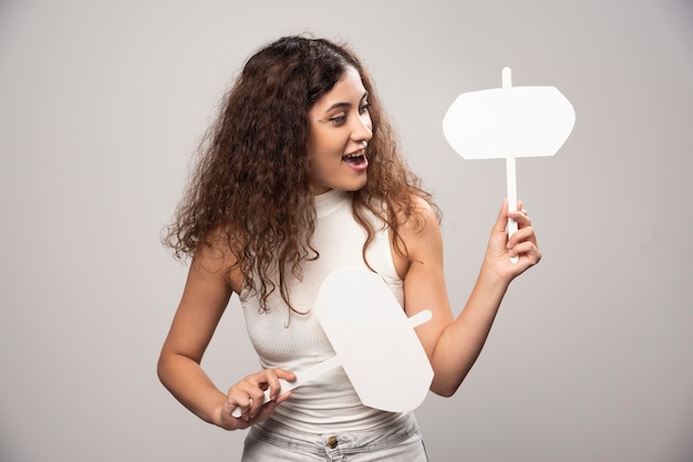 Jeune femme tenant deux affiches blanches vierges. Photo de haute qualité