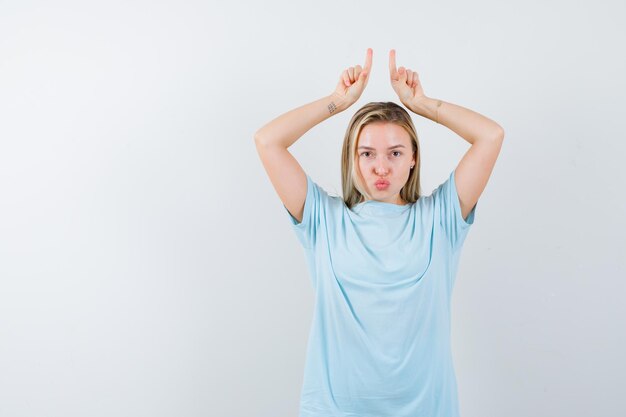 Jeune femme tenant les doigts au-dessus de la tête comme des cornes tout en faisant la moue des lèvres isolées