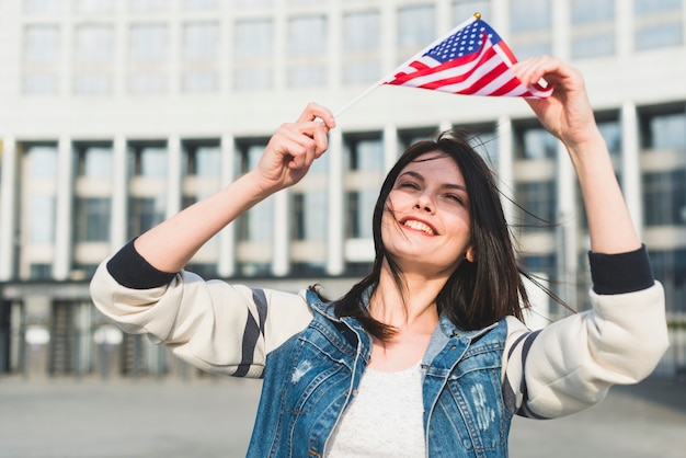 Jeune femme tenant un drapeau américain au-dessus de sa tête le 4 juillet