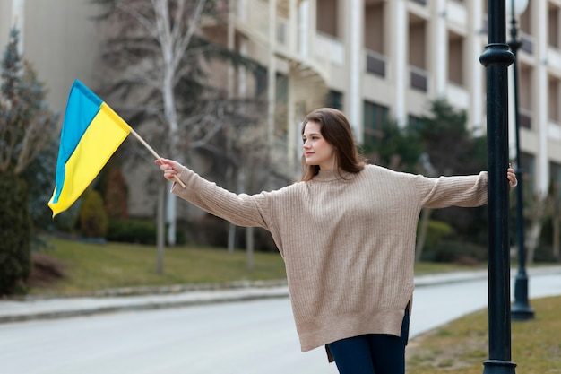 Jeune femme tenant un drapeau ukrainien coup moyen