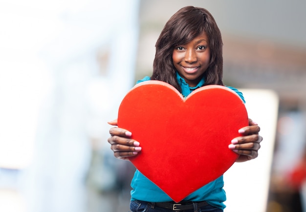 Jeune femme tenant un grand coeur rouge