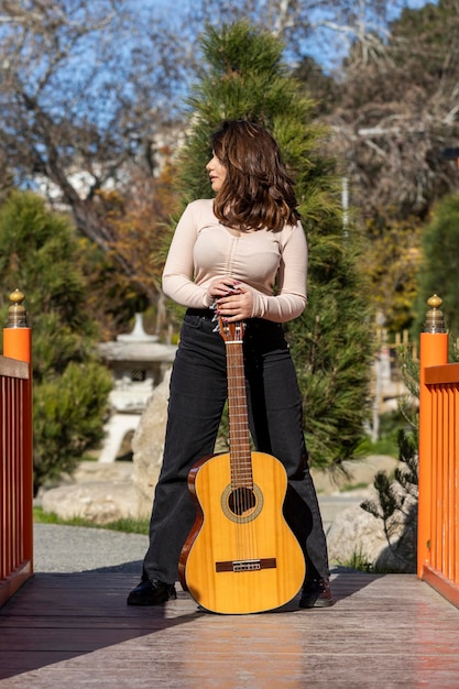 Jeune femme tenant une guitare et regardant loin Photo de haute qualité