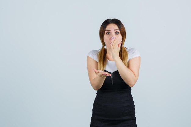 Jeune femme tenant la main sur la bouche et à la perplexité