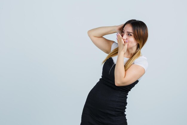 Jeune femme tenant la main sur la bouche et la tête et à la surprise