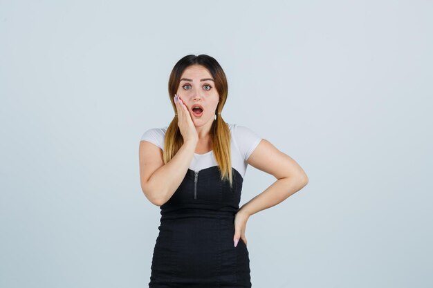 Jeune femme tenant une main sur la joue et l'air choqué