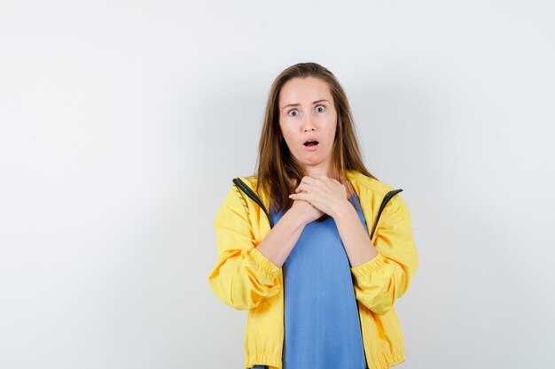 Jeune femme tenant la main sur la poitrine en t-shirt et à la surprise